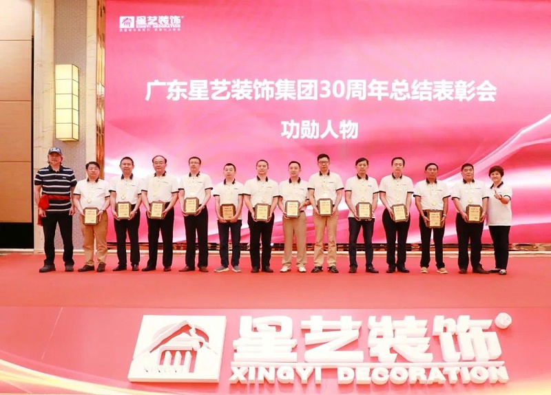 12 company staff of Xingyi Decoration who received the "Meritorious Person" award took a group photo on stage