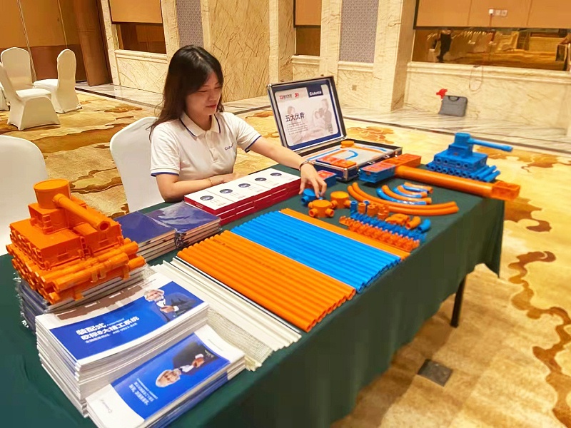 A female Ctube employee sits at a Ctube display table filled with brochures, conduits and fittings.